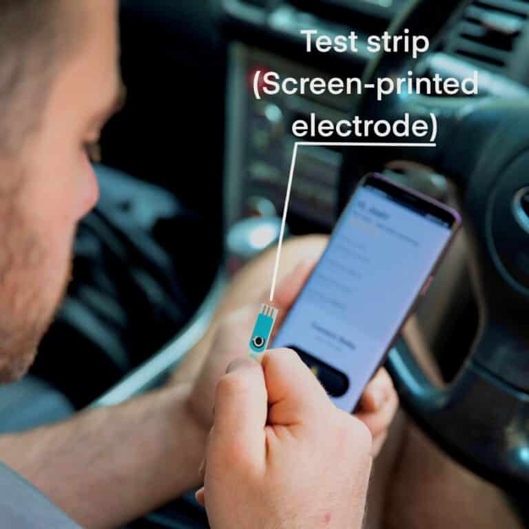 A Delta Sens user holding a test strip (screen printed electrode) while sitting in the car